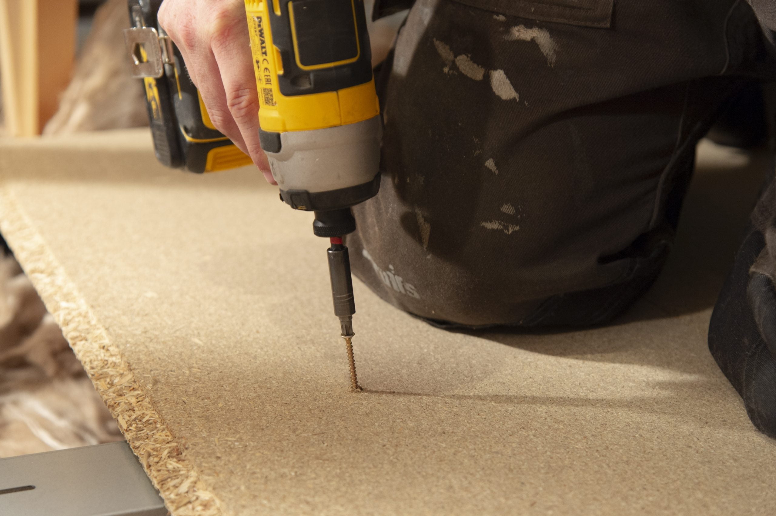 Loft Floor Board Installation: Need to Knows 6 A screw being drilled into a floor board with an electronic drill.