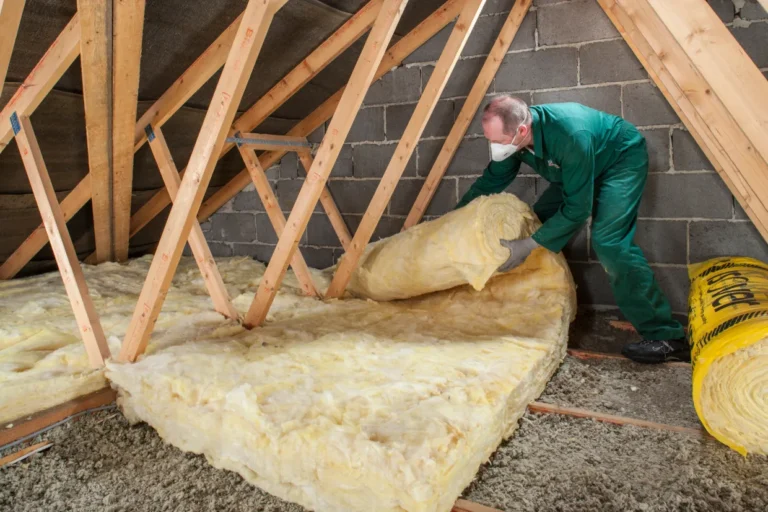 a man laying insulation on the loft floor to improve energy saving potential