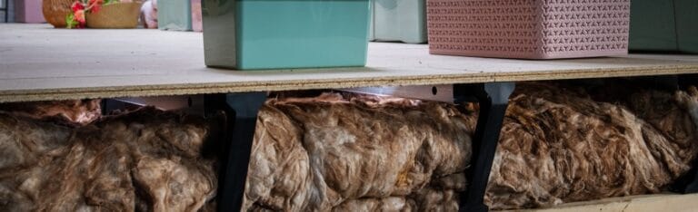 A raised loft floor with insulation underneath it and a storage box on top.